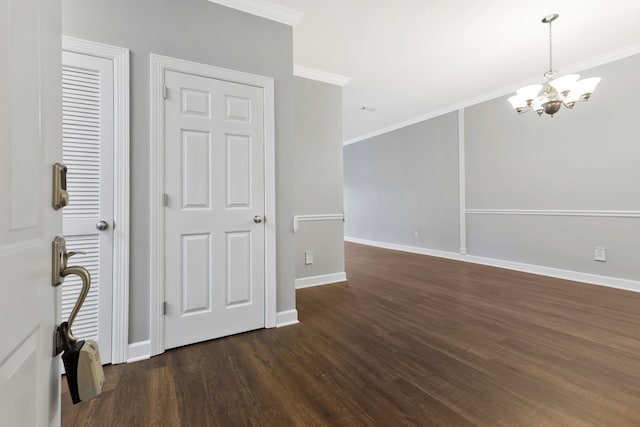 unfurnished room featuring dark wood-style floors, baseboards, ornamental molding, and a notable chandelier