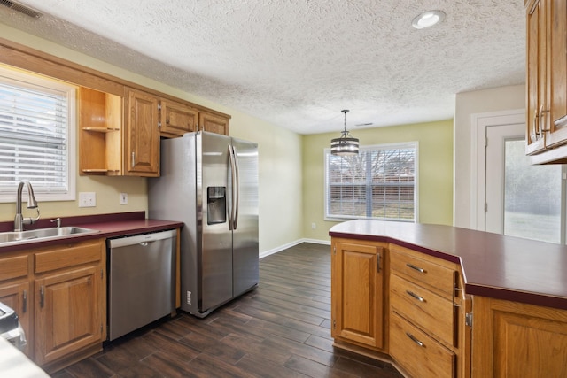 kitchen with visible vents, brown cabinetry, hanging light fixtures, stainless steel appliances, and a sink