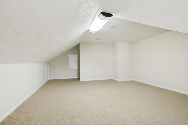 bonus room with lofted ceiling, light colored carpet, a textured ceiling, and baseboards