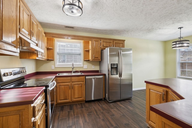 kitchen with a sink, appliances with stainless steel finishes, open shelves, brown cabinetry, and decorative light fixtures