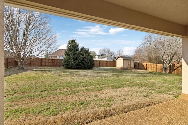 view of yard featuring an outbuilding, a fenced backyard, and a storage unit