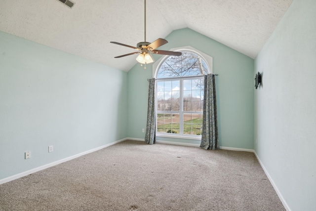 carpeted empty room featuring vaulted ceiling, a textured ceiling, plenty of natural light, and a ceiling fan