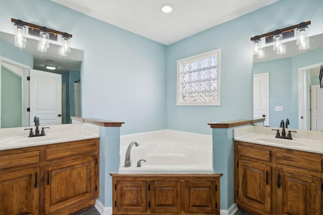 full bath featuring two vanities, a sink, and a bath