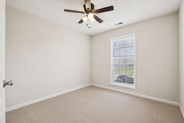 carpeted empty room with a ceiling fan, visible vents, a textured ceiling, and baseboards