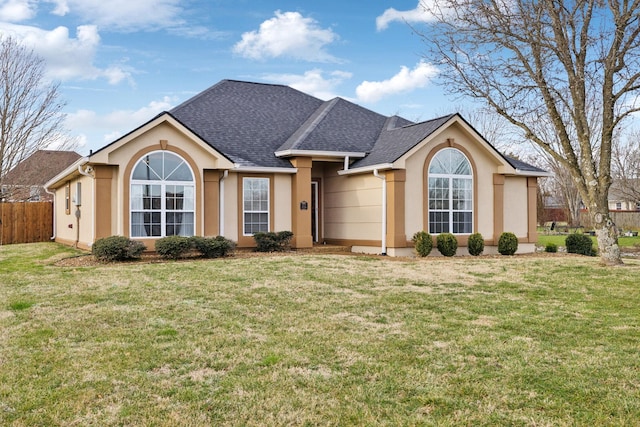 single story home featuring a shingled roof, a front yard, fence, and stucco siding