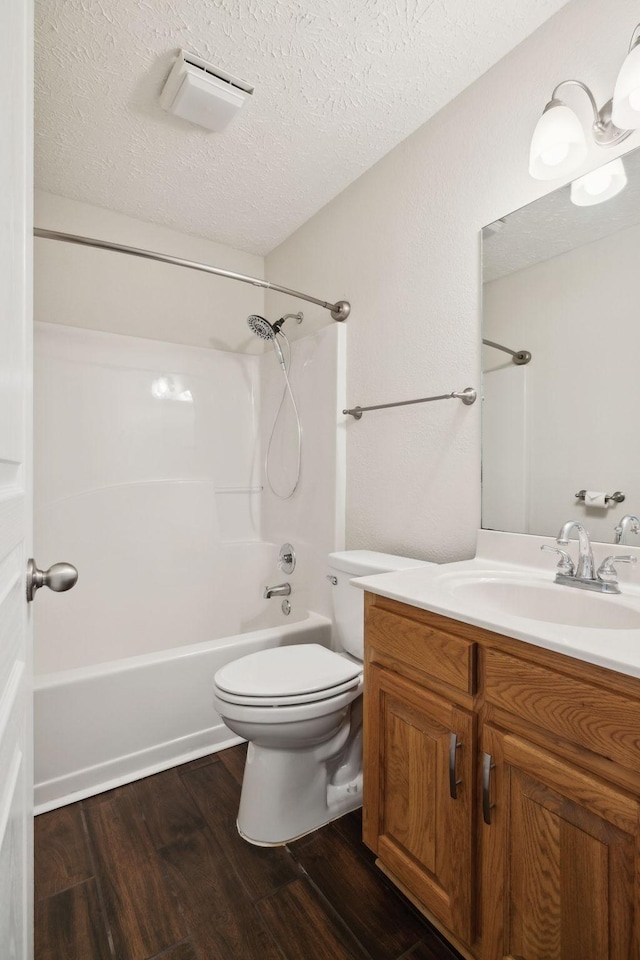 full bathroom with toilet, wood finished floors,  shower combination, a textured ceiling, and vanity