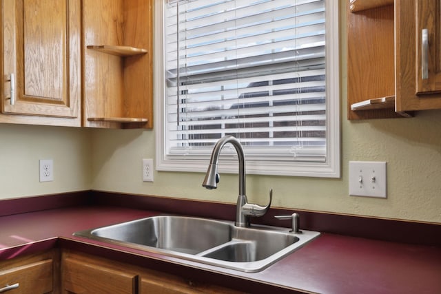 kitchen featuring brown cabinets, a sink, and a textured wall