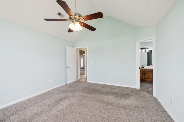 unfurnished bedroom featuring baseboards, visible vents, lofted ceiling, ensuite bath, and carpet flooring