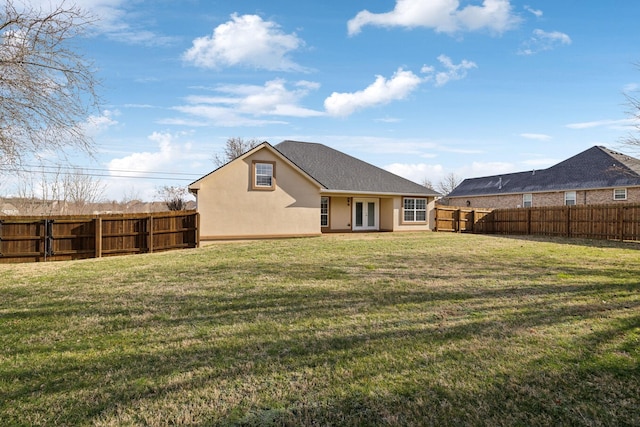 back of house with a lawn, a fenced backyard, and stucco siding