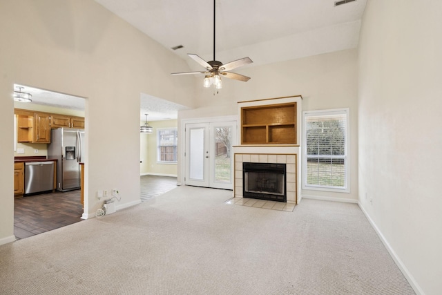 unfurnished living room with carpet floors, a fireplace, high vaulted ceiling, and baseboards