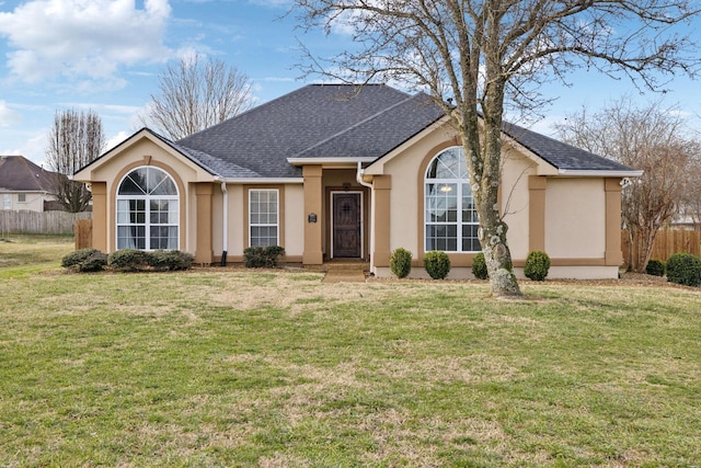 ranch-style house with roof with shingles, a front yard, fence, and stucco siding