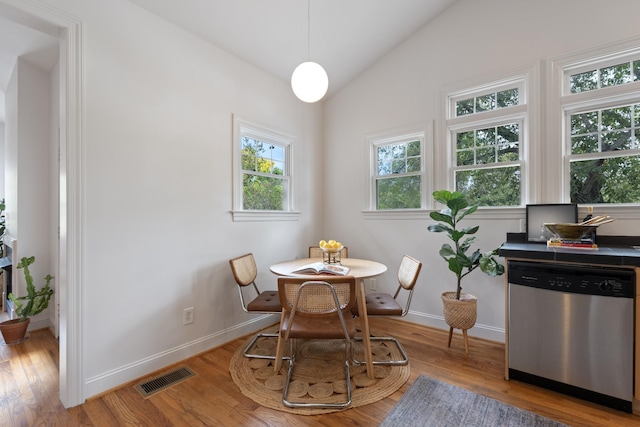 dining room with lofted ceiling, light wood-style flooring, visible vents, and baseboards