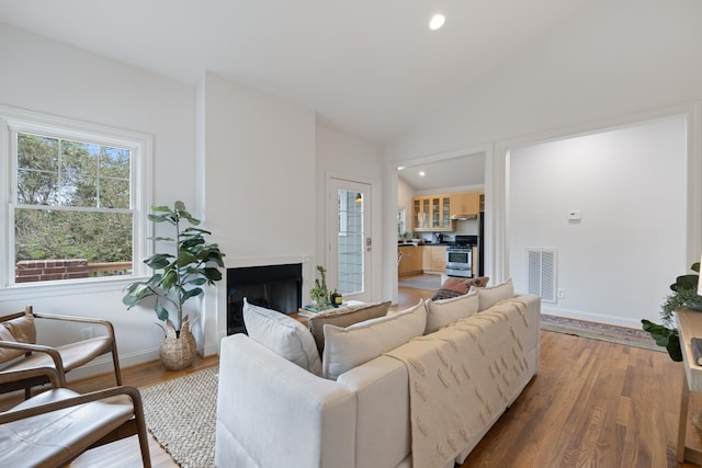 living room featuring lofted ceiling, recessed lighting, a fireplace, wood finished floors, and visible vents