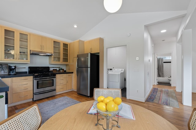 kitchen with stainless steel appliances, dark countertops, light brown cabinets, and glass insert cabinets