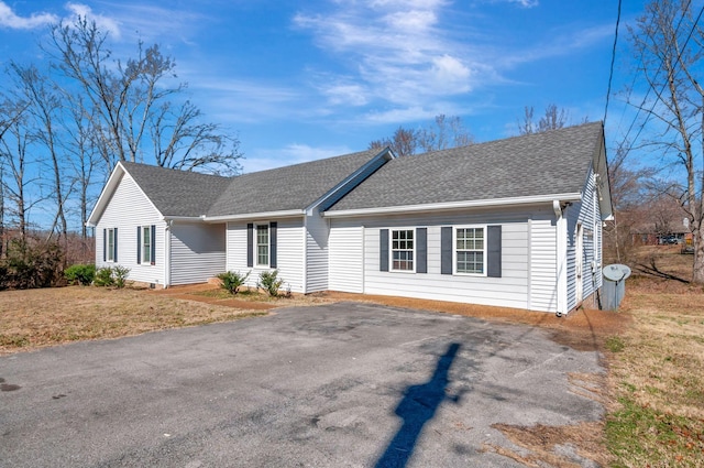 ranch-style home featuring a shingled roof, driveway, and a front lawn