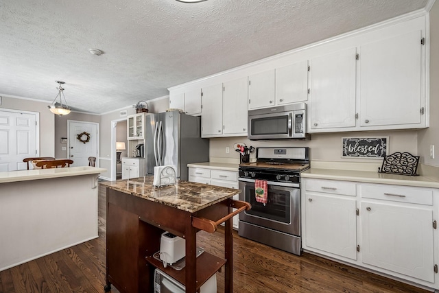 kitchen featuring stainless steel appliances, white cabinets, light countertops, dark wood-style floors, and decorative light fixtures