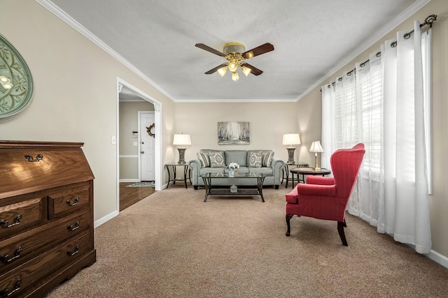 living area with a textured ceiling, carpet flooring, a ceiling fan, and crown molding