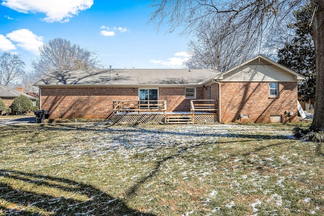 back of property with a deck, a yard, and brick siding