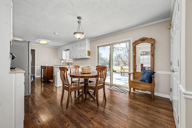 dining area with dark wood-style floors, ornamental molding, a textured ceiling, and baseboards