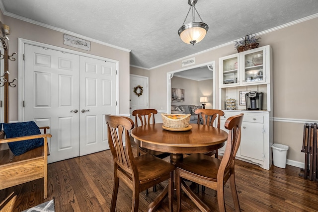 dining room featuring dark wood-style flooring, crown molding, and a textured ceiling