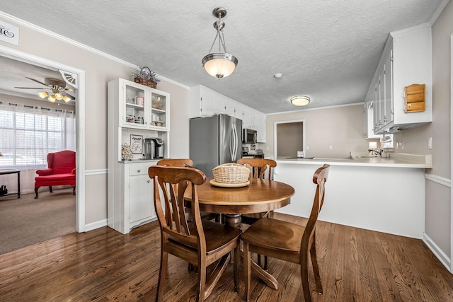 dining space featuring a textured ceiling, ornamental molding, dark wood finished floors, and a ceiling fan