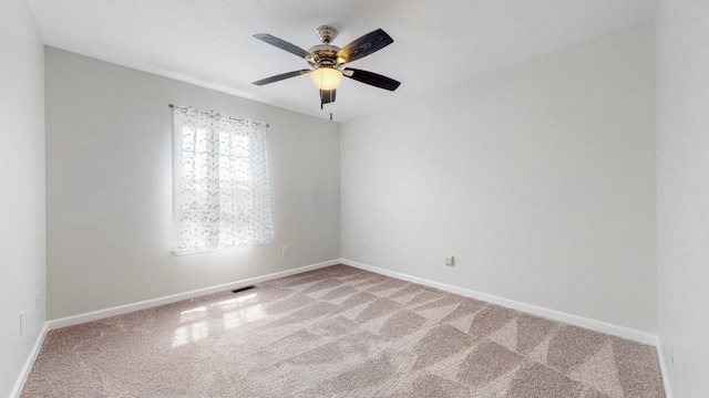 empty room featuring light carpet, ceiling fan, visible vents, and baseboards