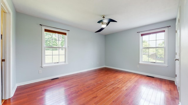 empty room featuring a wealth of natural light, wood finished floors, and visible vents