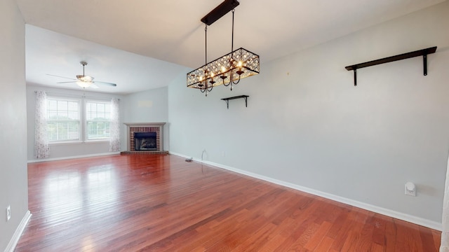 unfurnished living room featuring a brick fireplace, wood finished floors, and baseboards