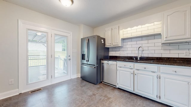 kitchen featuring visible vents, a sink, stainless steel appliances, white cabinetry, and backsplash