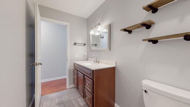bathroom with toilet, baseboards, and vanity