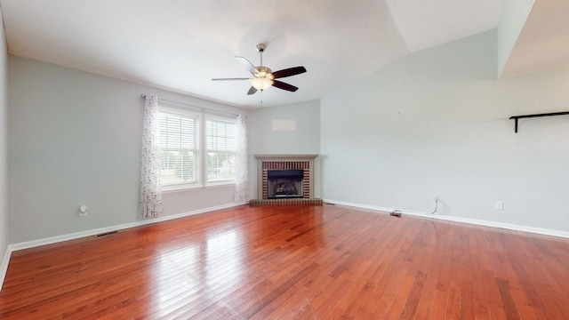 unfurnished living room with a fireplace, visible vents, vaulted ceiling, wood finished floors, and baseboards