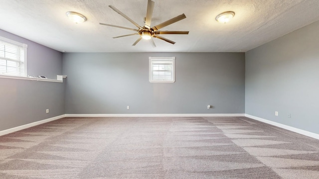 unfurnished room with a ceiling fan, light carpet, a textured ceiling, and baseboards