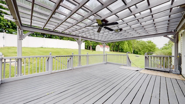 deck featuring a storage shed, a lawn, ceiling fan, fence, and a pergola