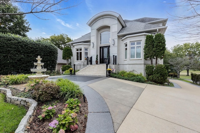 view of front of property with driveway, a shingled roof, and brick siding