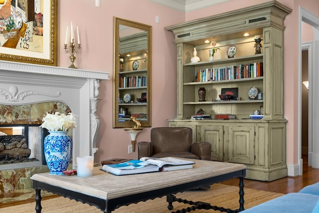 sitting room featuring ornamental molding, built in shelves, and wood finished floors