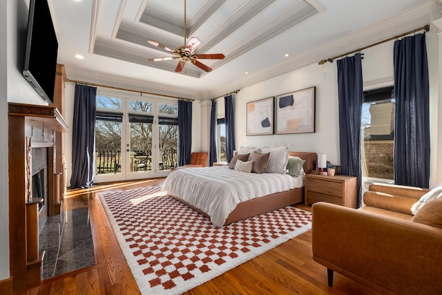 bedroom with dark wood-style floors, a fireplace, a raised ceiling, and crown molding