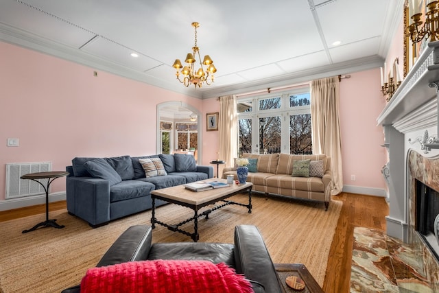 living area with visible vents, arched walkways, a premium fireplace, ornamental molding, and light wood-style floors