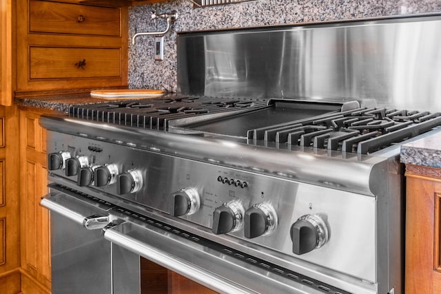 room details with brown cabinets, backsplash, and high end stainless steel range