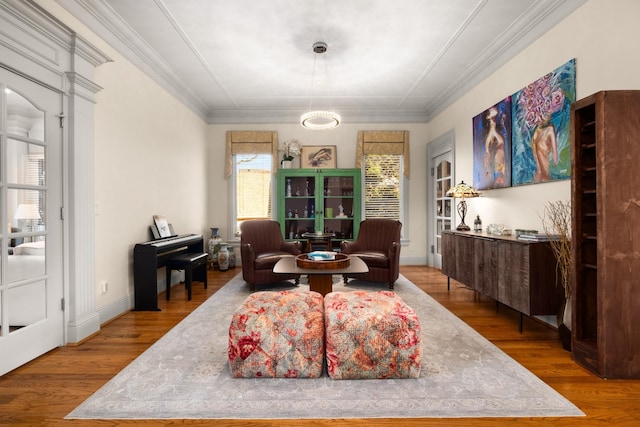 living area featuring crown molding, baseboards, and wood finished floors