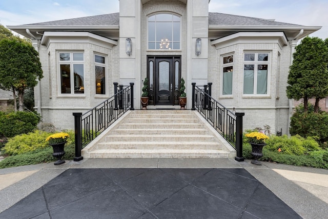 property entrance featuring brick siding and roof with shingles