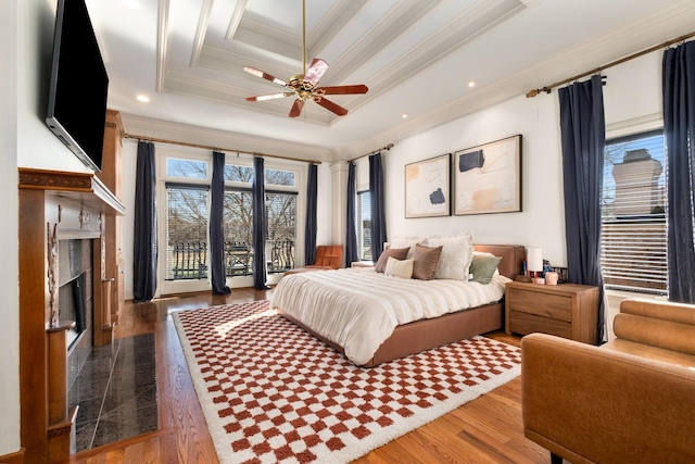 bedroom featuring a premium fireplace, wood finished floors, access to outside, ornamental molding, and a raised ceiling