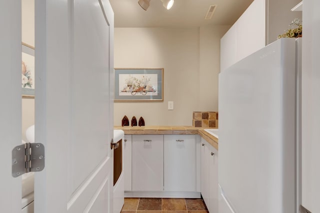 interior space with visible vents, white cabinets, light countertops, and freestanding refrigerator