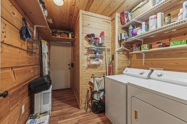 clothes washing area featuring laundry area, wooden ceiling, wood finished floors, wood walls, and separate washer and dryer