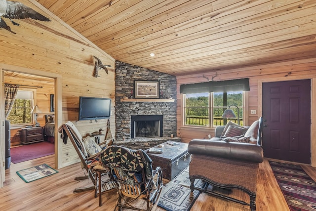 living area featuring wooden walls, wooden ceiling, vaulted ceiling, light wood-type flooring, and a fireplace