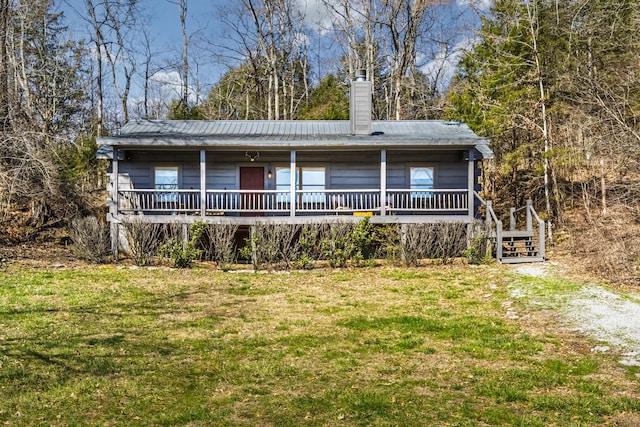 view of front of house with metal roof, a front lawn, and a chimney