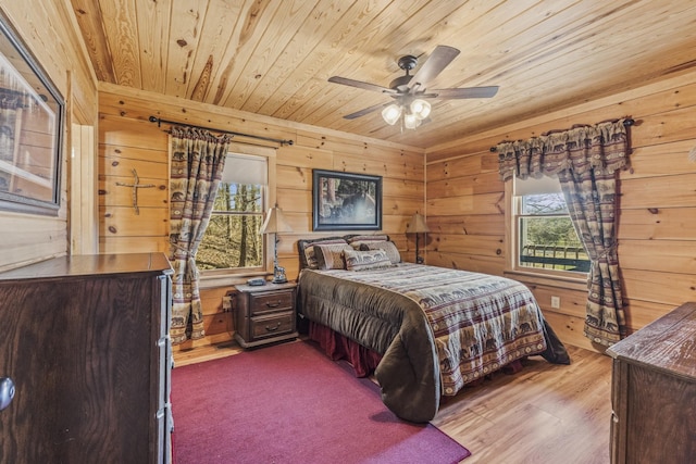 bedroom featuring light wood-type flooring, wooden ceiling, a ceiling fan, and wood walls