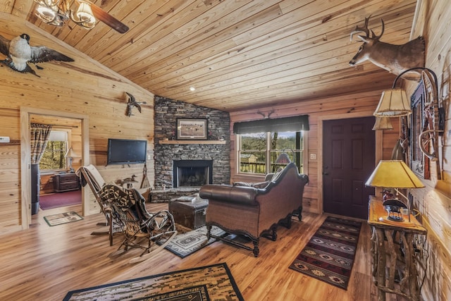 living area with wooden ceiling, wooden walls, wood finished floors, and a stone fireplace