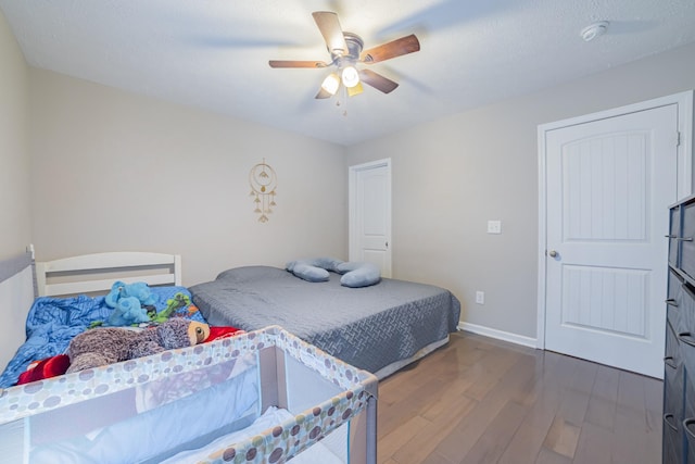 bedroom with ceiling fan, wood finished floors, and baseboards