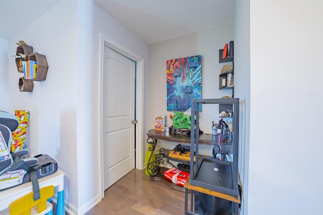 interior space featuring a textured ceiling, wood finished floors, and baseboards