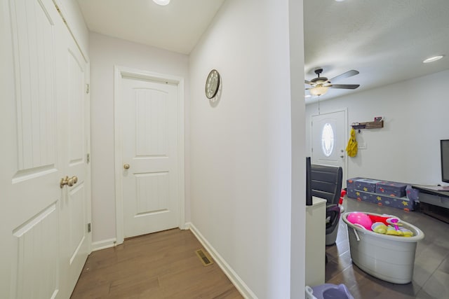 corridor with dark wood-style floors, visible vents, and baseboards